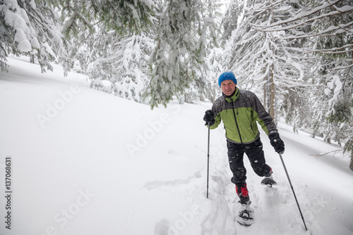 Joyful traveler running snowshoeing in deep snow
