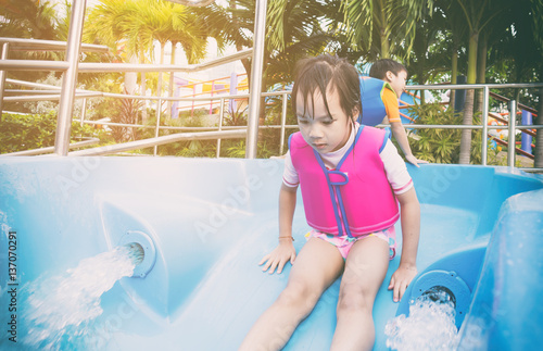 Asian girl is sliding down the water sldie photo