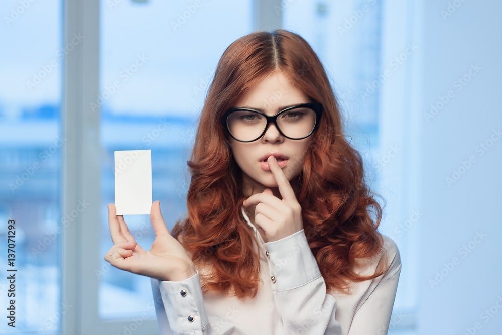 Fototapeta premium red-haired woman and badge in her hand, index finger near the lips