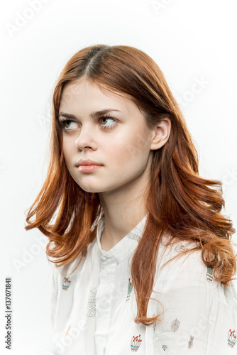 red-haired woman on a light background looks up