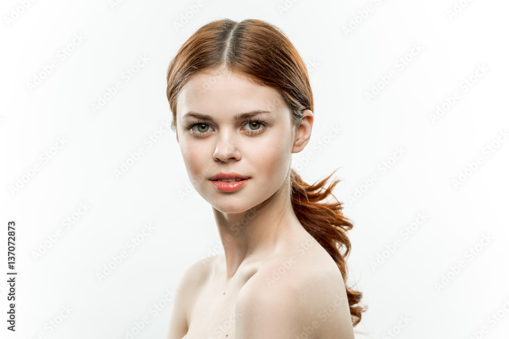 red-haired woman on a light background looks at the camera red-haired woman on a light background looks at the camera