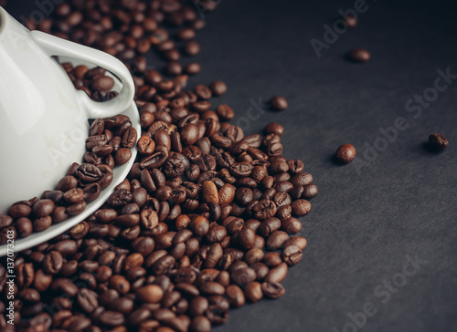 coffee beans on a gray background and a mug with a saucer