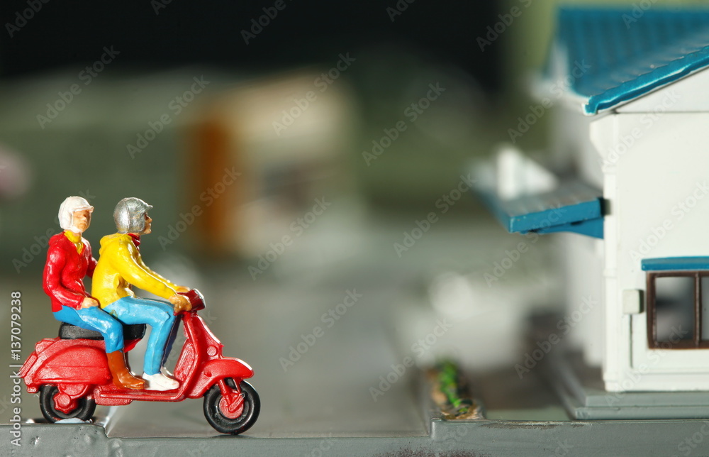 The miniature figure model of man riding scooter red color in the city road  represent the figure model toy travel and transportation concept related  idea. Stock Photo