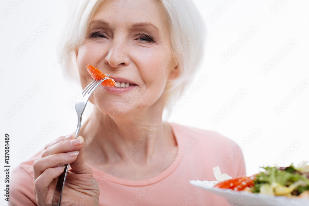 Portrait of aged female while eating tomato Portrait of aged female while eating tomato