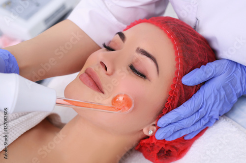 Receiving electric darsonval facial massage procedure.