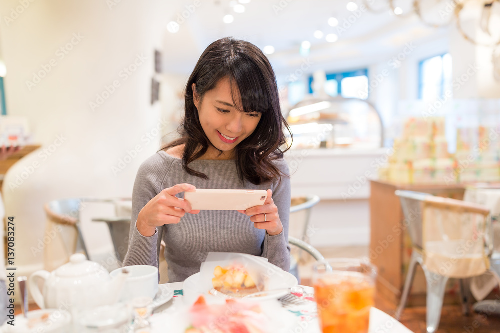 Woman taking photo on her cake in restaurant Woman taking photo on her cake in restaurant