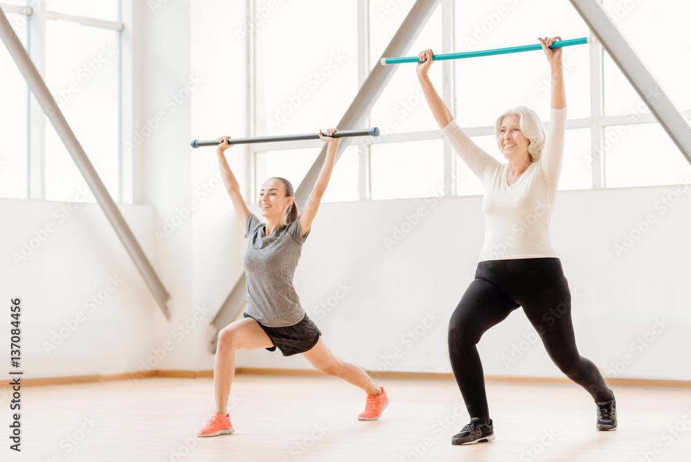 Cheerful sporty women working out with gymnastic sticks
