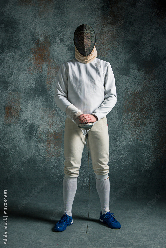 The man wearing fencing suit with sword against gray