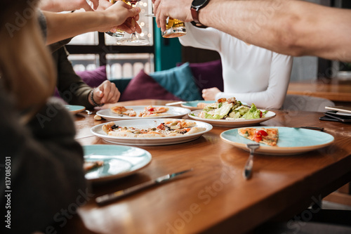 Cropped photo of friends eating and drinking alcohol.