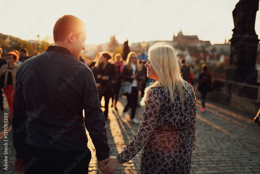 Obraz premium young woman and man walking on the old street at sunset