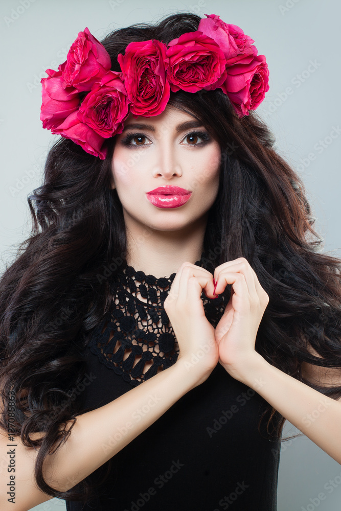 Naklejka premium Beautiful Model Making a Heart and Blowing a Kiss. Brunette Woman with Curly Hair and Makeup, Love Concept
