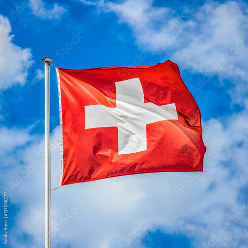 Obraz na płótnie Flag of Switzerland waving in the wind on a sunny day with blue sky and clouds w salonie