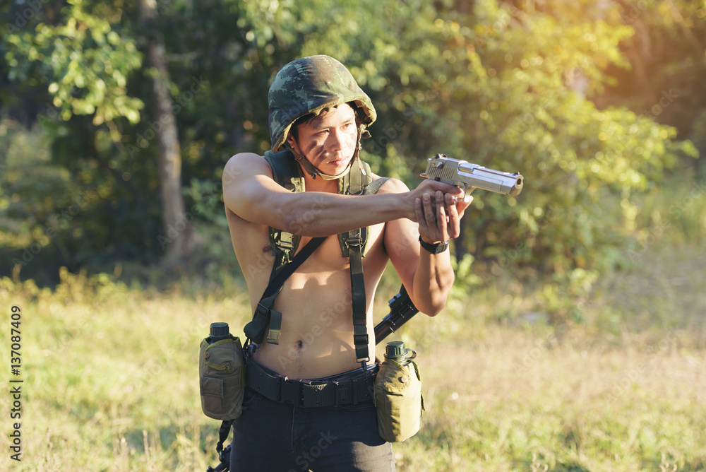 Man aiming with rifle while standing in forest