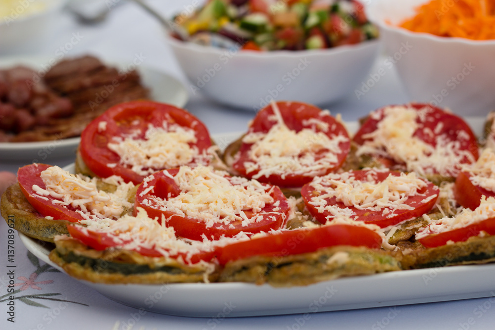 Meal of tomatoes and zucchini with cheese on table Meal of tomatoes and zucchini with cheese on table