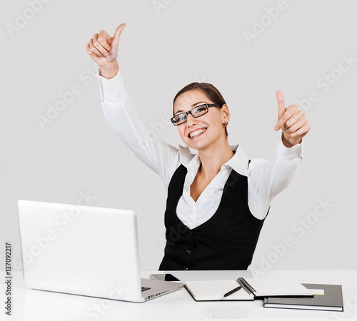 Canvas Print Portrait of a young beautiful business woman showing thumbs up sign, over gray b