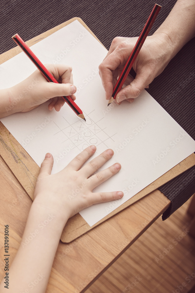 Child and adult play tic-tac-toe Child and adult play tic-tac-toe