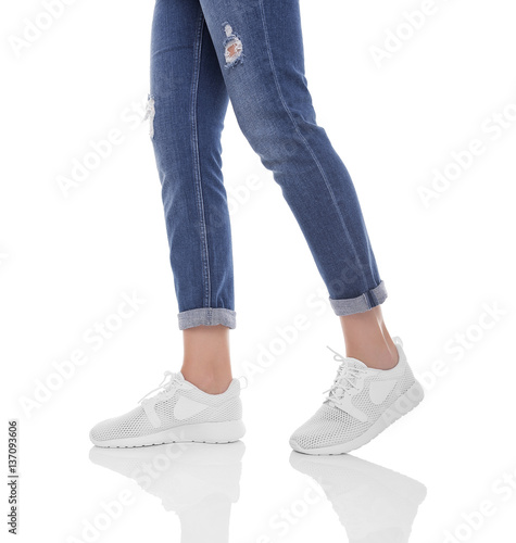 Women's legs in jeans and sneakers.