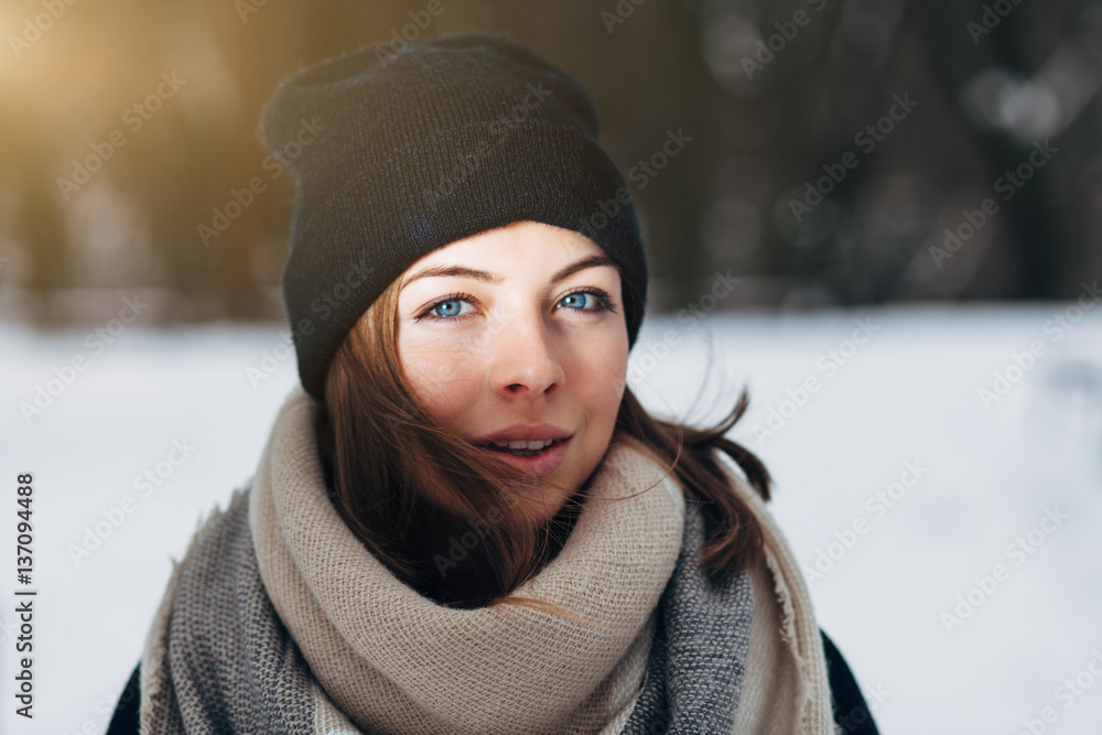 Portrait of a beautiful girl with blue eyes in a black hat and a scarf in the winter park Portrait of a beautiful girl with blue eyes in a black hat and a scarf in the winter park