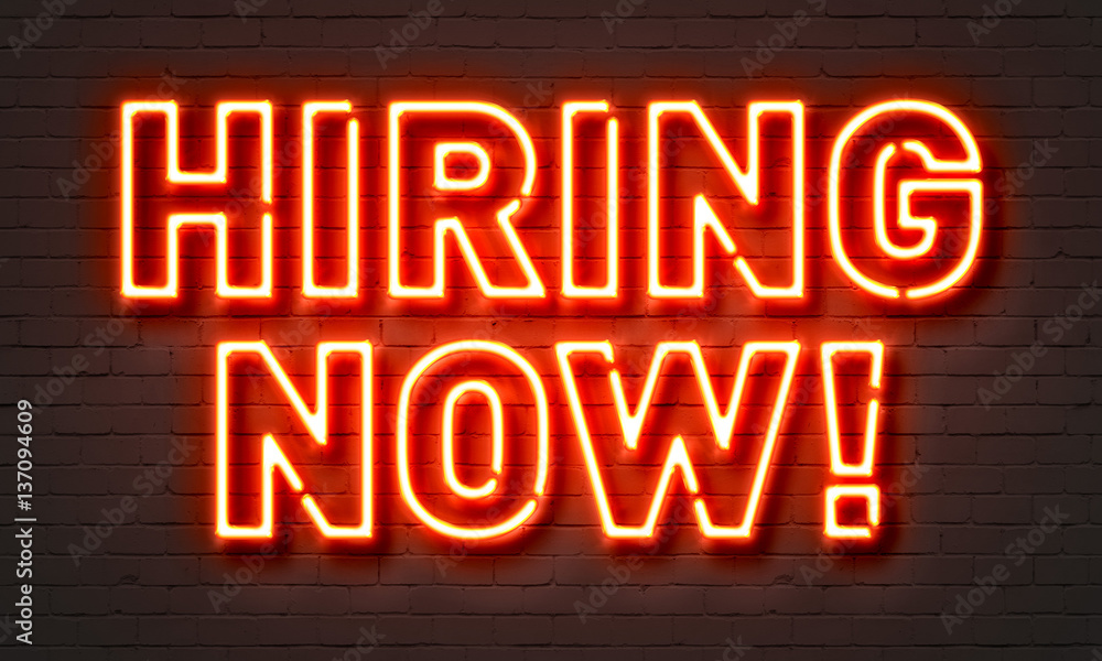 Hiring now neon sign on brick wall background.