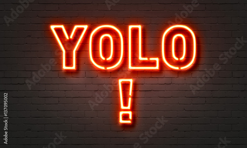 YOLO neon sign on brick wall background. photo