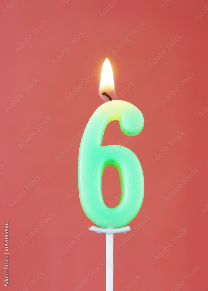 Burning wax candle as number six on red background Burning wax candle as number six on red background