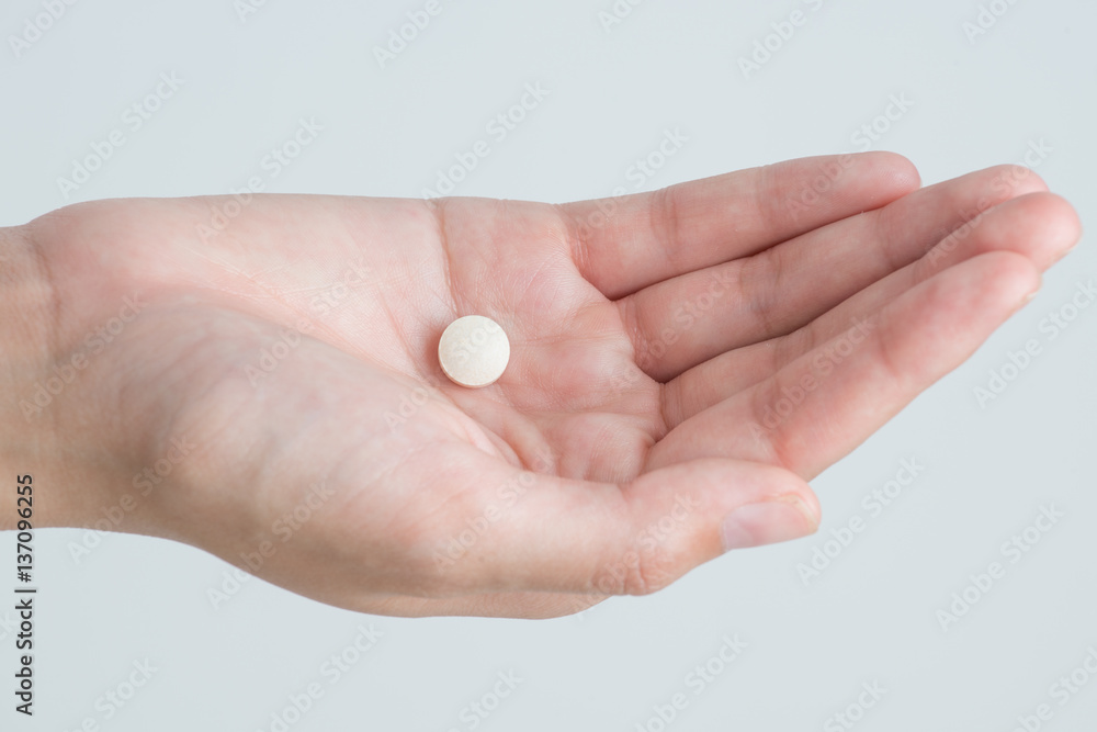 Closeup woman hand holding white medicine and pills isolated on white background Closeup woman hand holding white medicine and pills isolated on white background