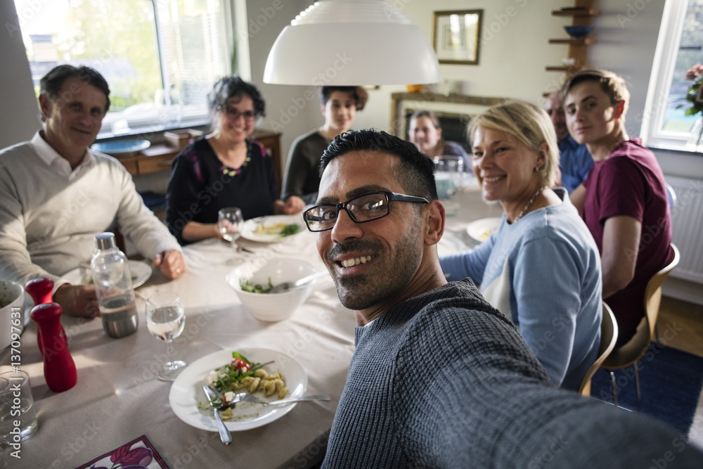 Portrait of smiling man taking selfie with family and friends at dinner party Portrait of smiling man taking selfie with family and friends at dinner party