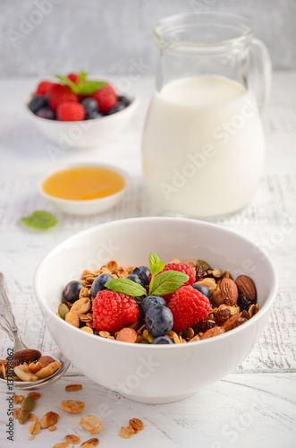 Homemade granola with fresh berries on white wooden background, selective focus