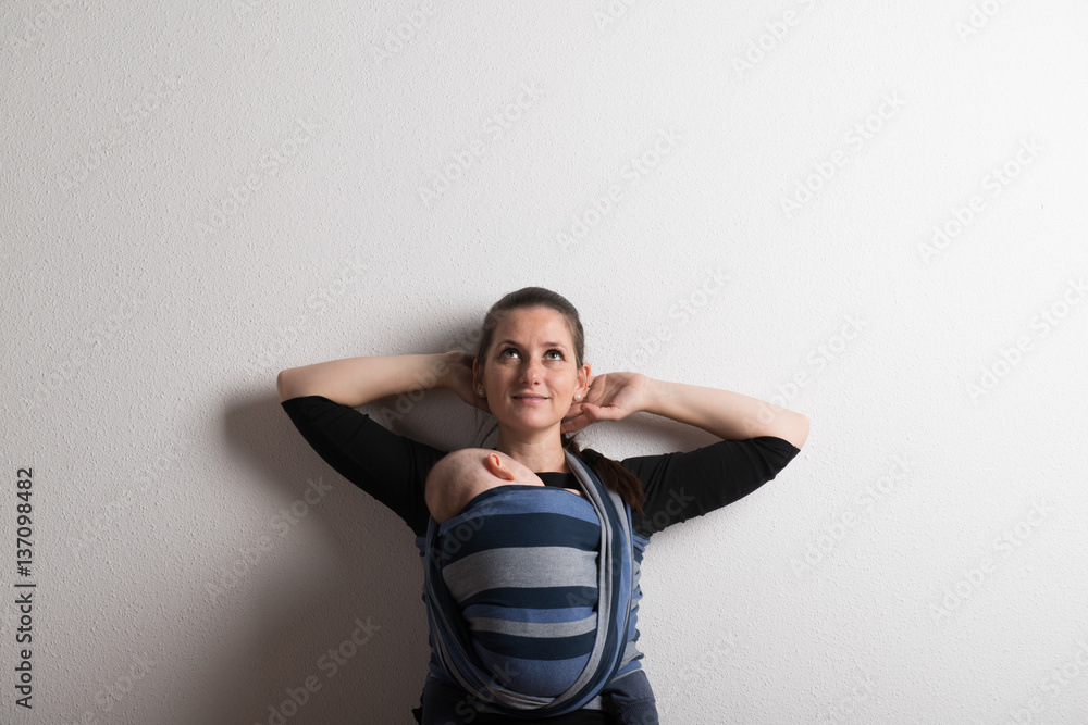 Mother with her baby son sleeping in sling. Studio shot. Mother with her baby son sleeping in sling. Studio shot.