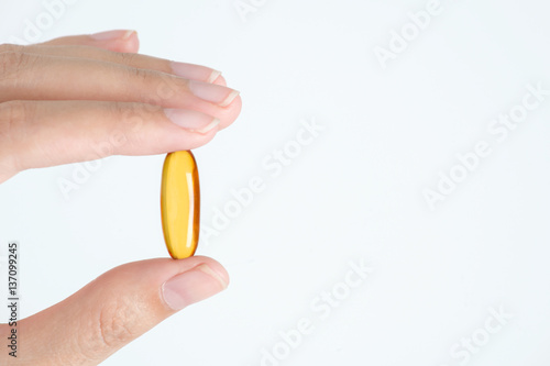 Closeup woman hand show yellow pills capsules or fish oil isolated on white background