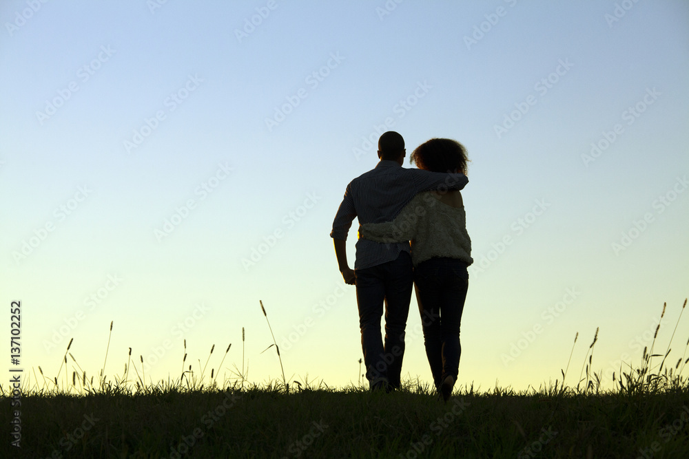 Rear view of young couple holding each other against background of clear evening sky Rear view of young couple holding each other against background of clear evening sky