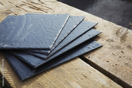 A pile of slate tiles on a wooden surface. 
