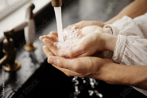 Couple running hands under water faucet