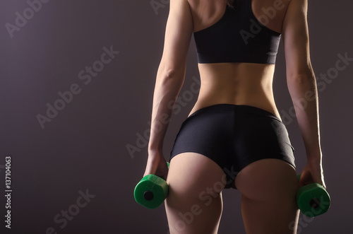 Athletic woman with toned buttocks on a gray background, closeup.