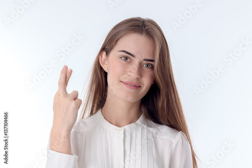 the girl smiles and holds his hand raised with crossed fingers is isolated on a white background