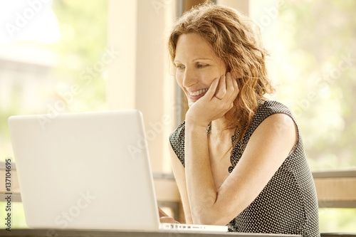 Smiling woman looking at laptop photo
