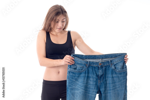 young girl in black top holds big pants isolated on white background