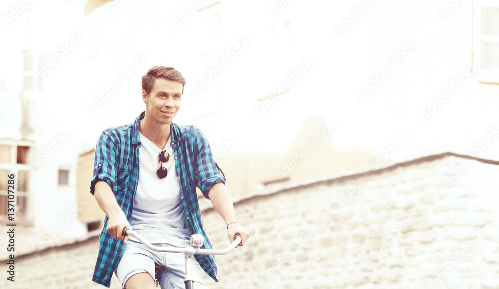 Attractive and handsome hipster riding a bicycle around town. Traveling, vacation concept. Attractive and handsome hipster riding a bicycle around town. Traveling, vacation concept.