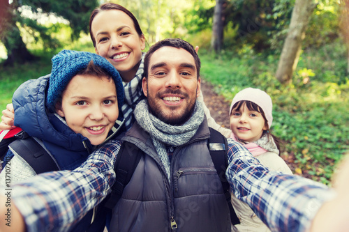 family with backpacks taking selfie and hiking