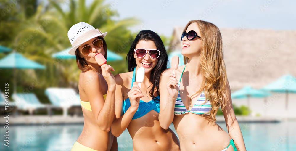 group of smiling women eating ice cream on beach