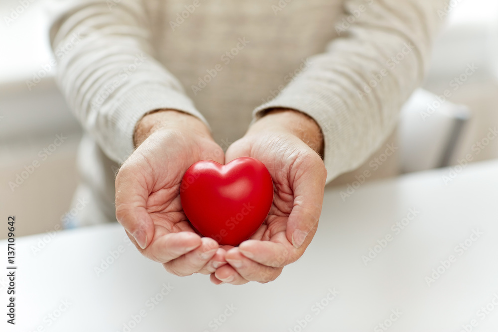 close up of senior man with red heart in hands close up of senior man with red heart in hands