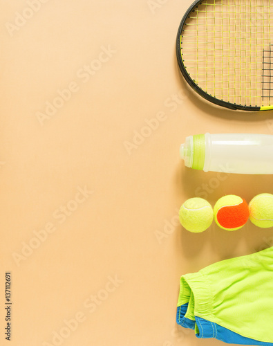 Kids tennis stuff on cream background. Sport, fitness, tennis, healthy lifestyle, sport stuff. Lime trainers, tennis balls, lime athletic shorts, sports bottle. Flat lay, top view. © Elena