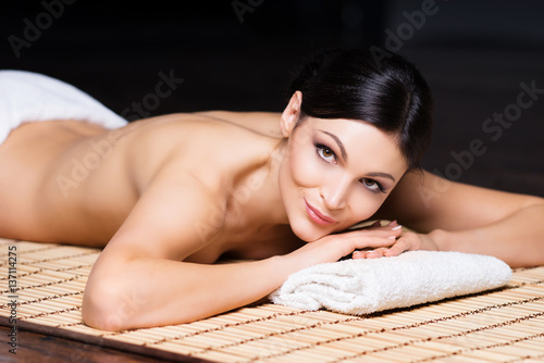Beautiful, young and healthy woman in spa salon. Massage treatment over black background. Spa, health and healing concept.