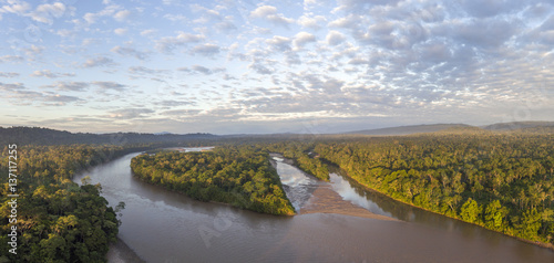 Aerial view of the Rio Napo at dawn in the Ecuadorian Amazon with the first rays of the sun illuminating the forest canopy.