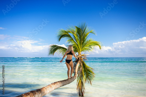 Fototapeta Naklejka Na Ścianę i Meble -  young girl walks down the palm tree above the sea