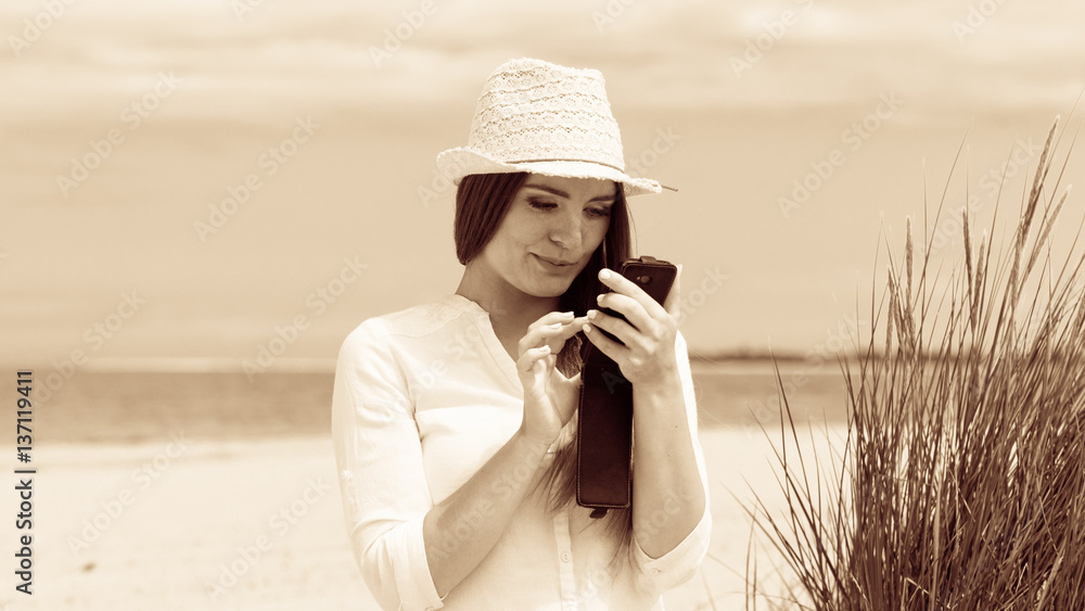 Woman on beach texting on smartphone.