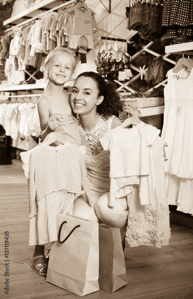 Fototapeta premium Happy woman with small child holding clothes