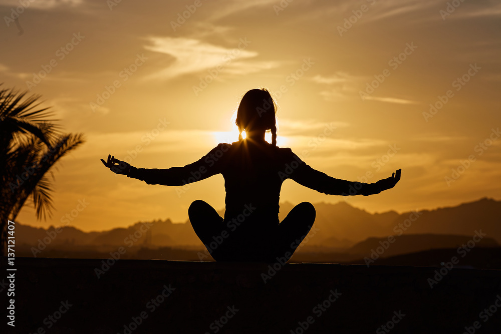 Sports and healthy lifestyle concept. Young, beautiful woman does yoga at sunset