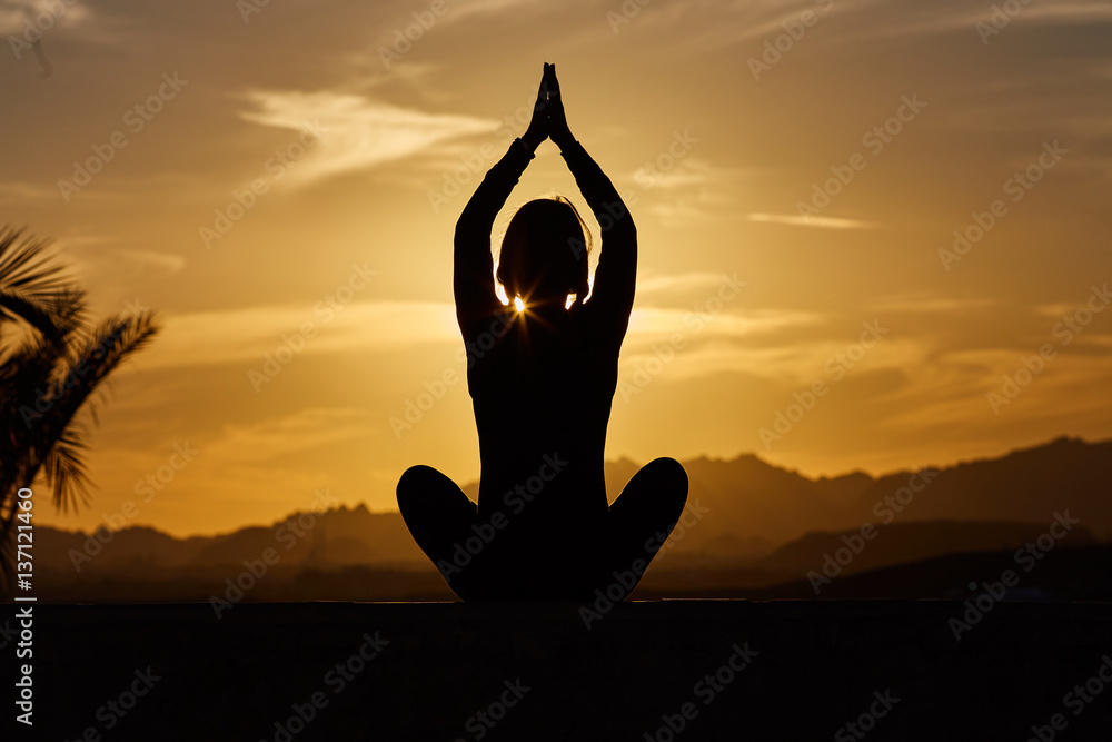 Sports and healthy lifestyle concept. Young, beautiful woman does yoga at sunset