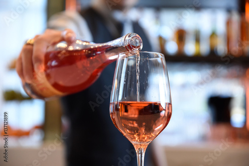 Waiter pouring glass of rose wine